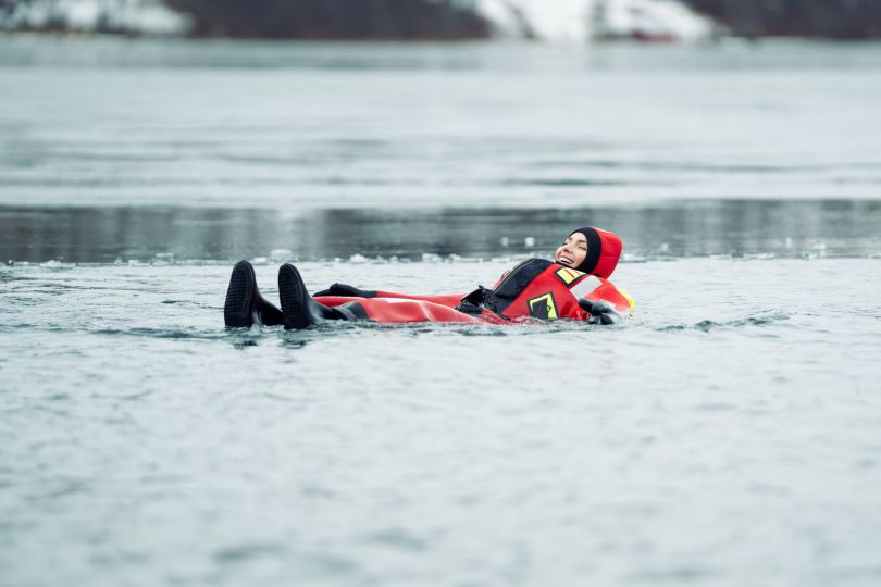 People floating over frozen lake in theraml warm suits