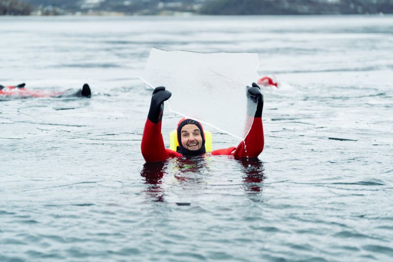 Man holding piece of ice while floathing in frozen water