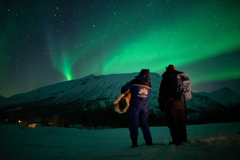 Two peole standing and looking at Northern Lights