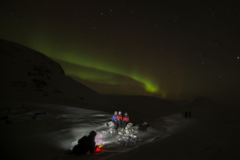 People taking picture in nature under Northern lights