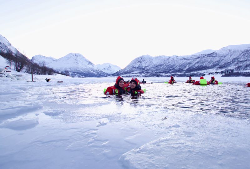 People floating over frozen lake in theraml warm suits