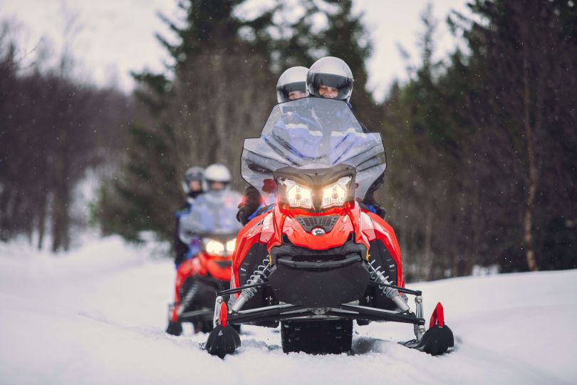 People driving Snowmobiles through snowy natures