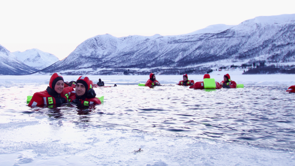 People floating over frozen lake in theraml warm suits