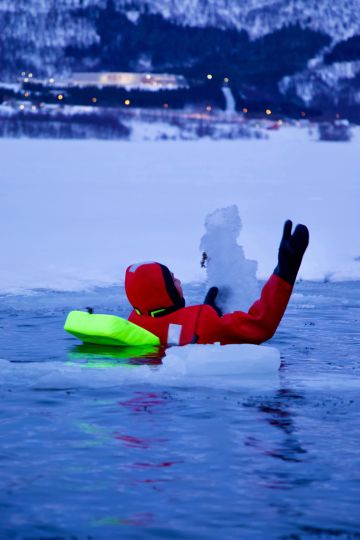 People floating over frozen lake in theraml warm suits