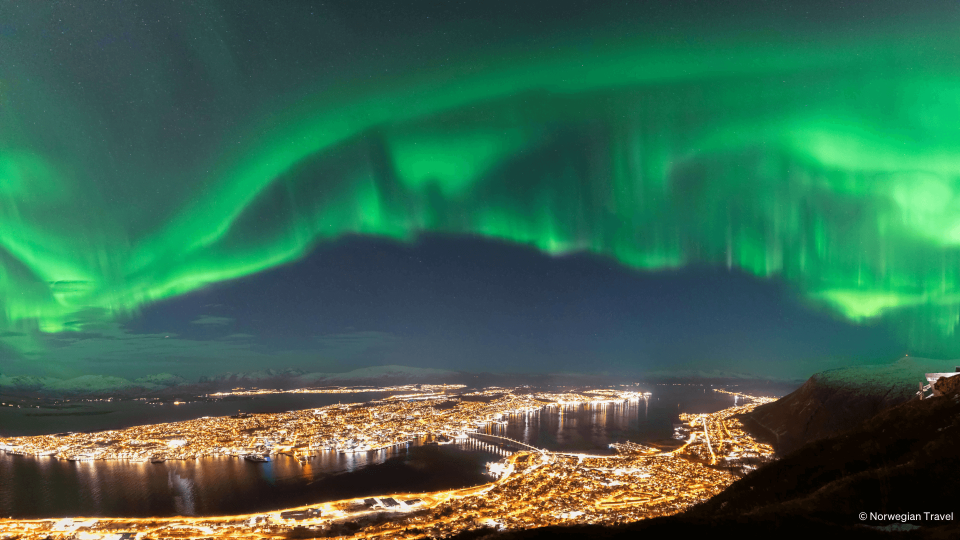Panoramic photo of Tromsø with northern lights in the sky from the Cable car.