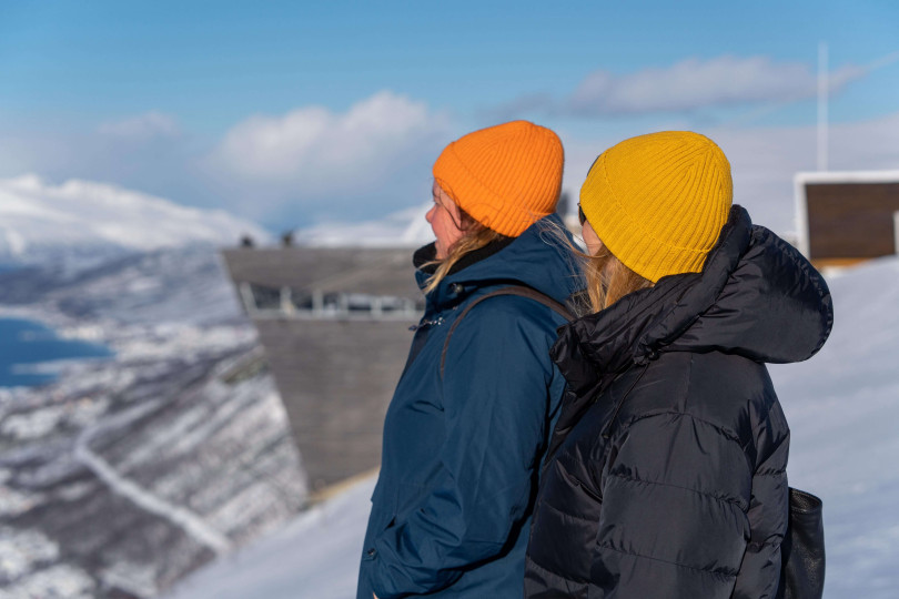 Two people dressed wamrly looking at Tromsø