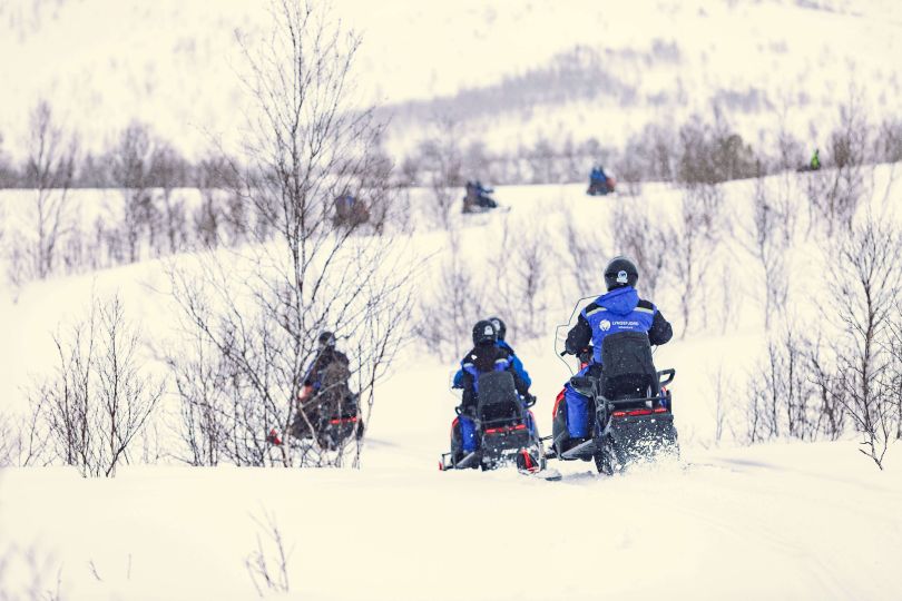 People driving Snowmobiles through snowy natures