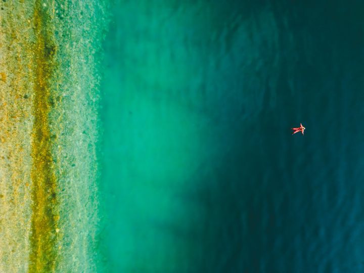 person floating in a fjord under the midnight sun