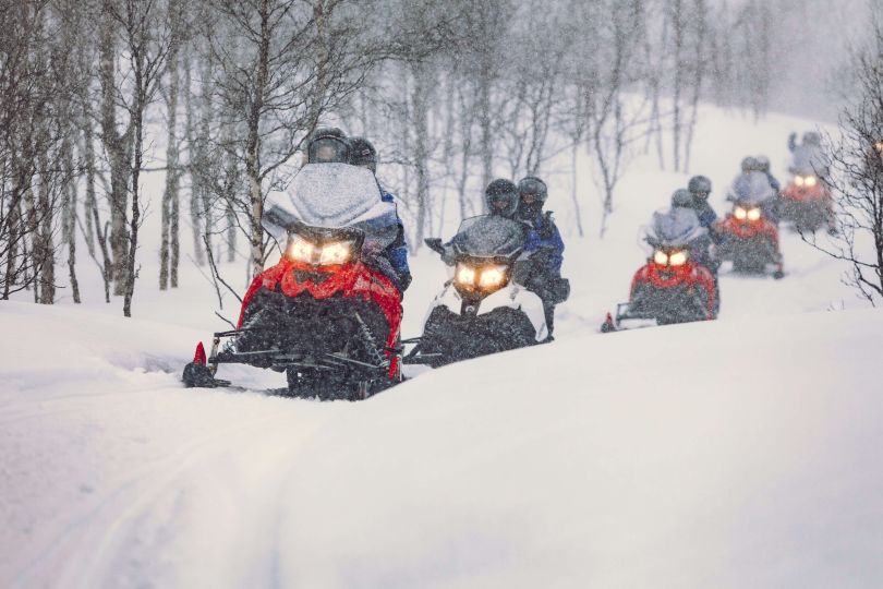 People driving Snowmobiles through snowy natures