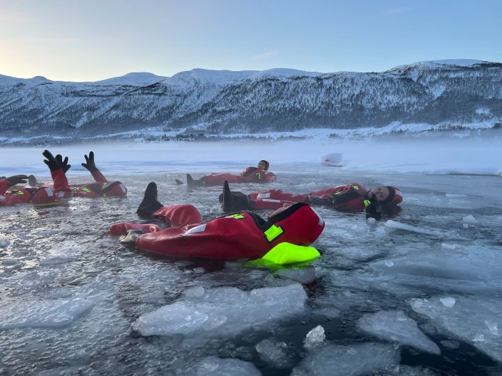 People floating over frozen lake in theraml warm suits